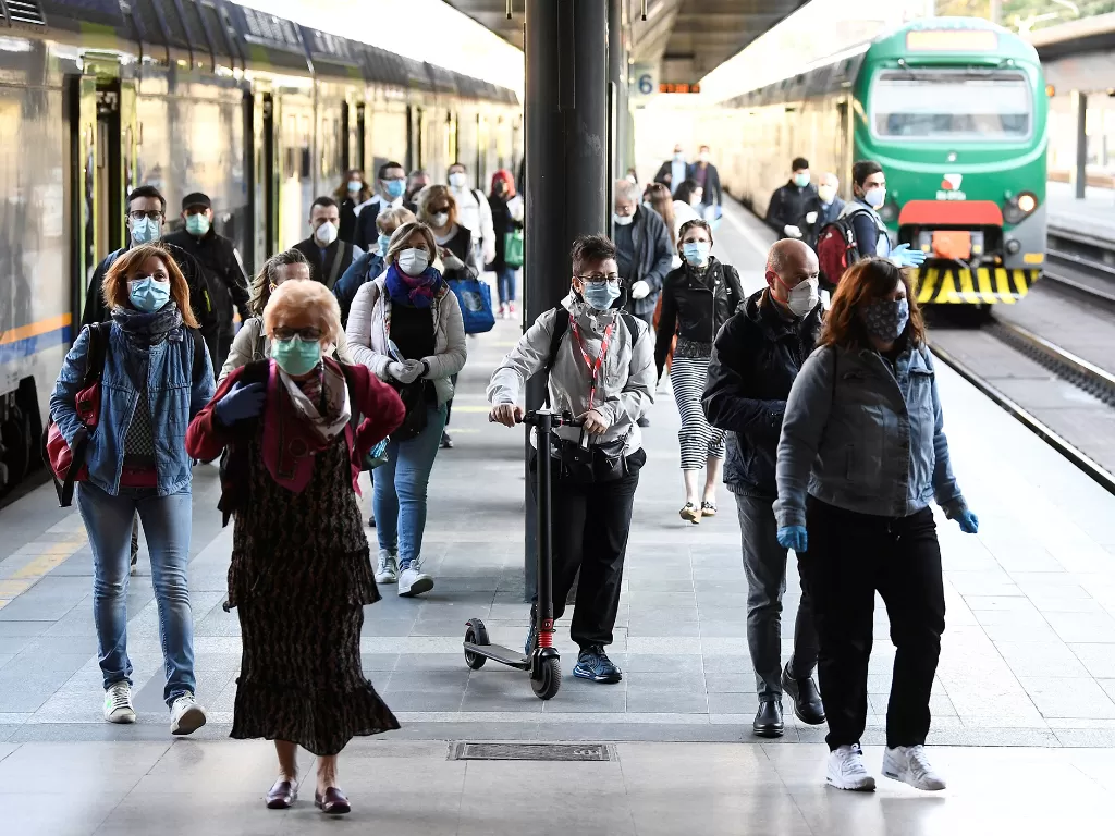 Sejumlah warga Italia kembali beraktivitas dengan memakai masker setelah penghentian lockdown, di Milan, Italia 4 Mei 2020. (REUTERS/Flavio Lo Scalzo)