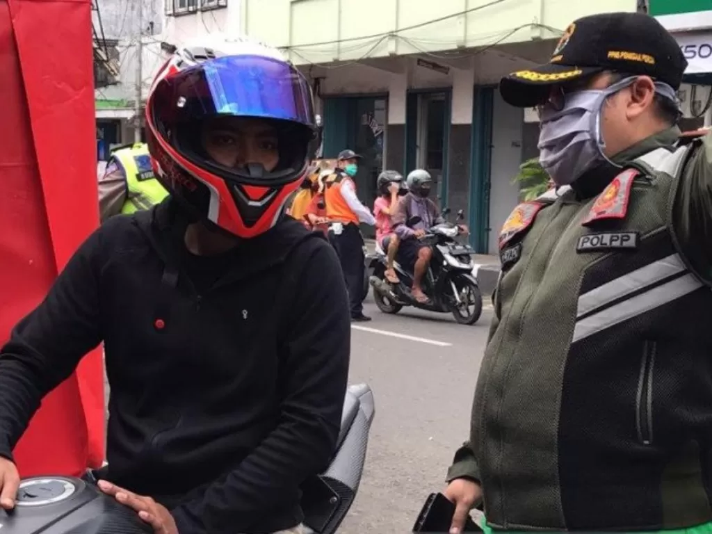 Kasatpol PP Kota Sukabumi, Jawa Barat saat menegur pengendara sepeda motor yang tidak menggunakan masker saat melintas di Jalan Ahmad Yani untuk putar arah. (ANTARA/Aditya Rohman)