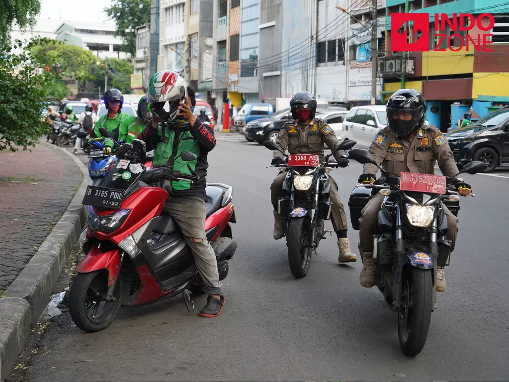 Petugas gabungan Satpol PP, Polisi dan Dinas Perhubungan melakukan penertiban kerumunan warga di sepanjang Jalan Hayam Wuruk, Jakarta, Rabu (15/4/2020). (INDOZONE/Arya Manggala)