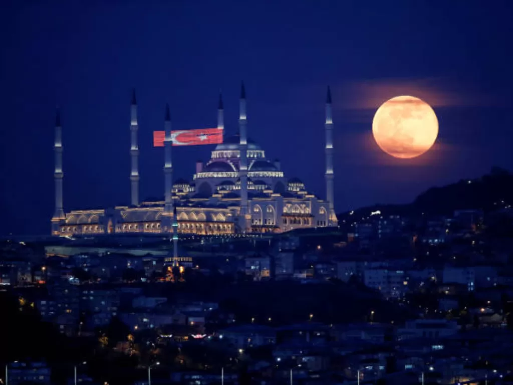 Bulan purnama, juga dikenal sebagai Supermoon atau Flower Moon, terlihat di atas Masjid Camlica selama penyebaran penyakit virus corona (COVID-19), di Istanbul, Turki, 7 Mei 2020. (REUTERS/Umit Bektas)