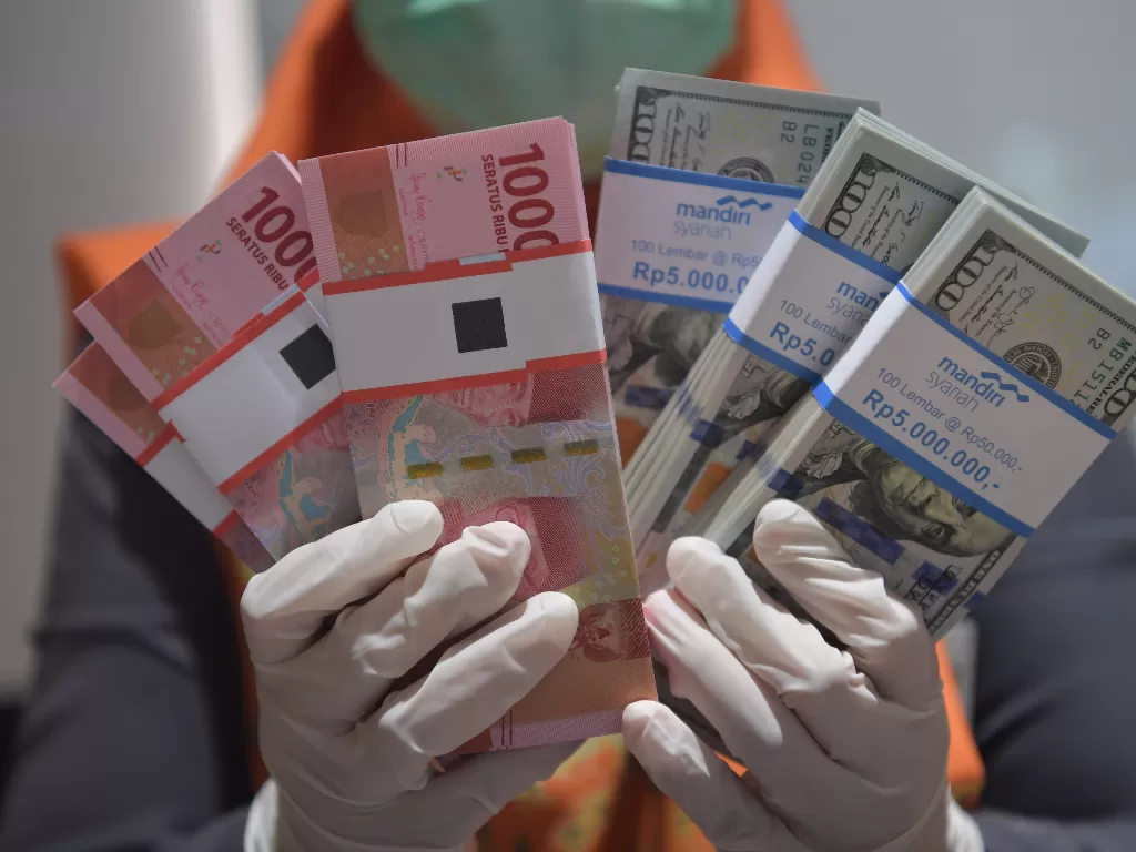 Karyawan menunjukkan uang rupiah dan dolar AS di Bank Mandiri Syariah (ANTARA FOTO/Nova Wahyudi)
