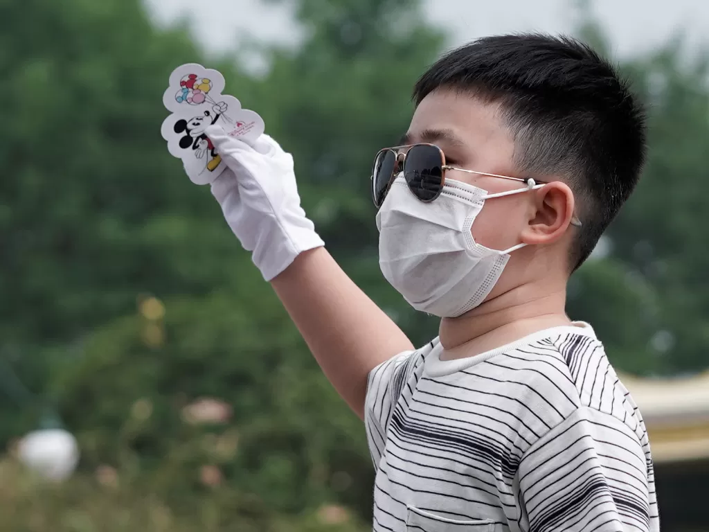 Seorang anak memakai masker dan kacamata di Disneyland Shangai. (REUTERS/Aly Song)