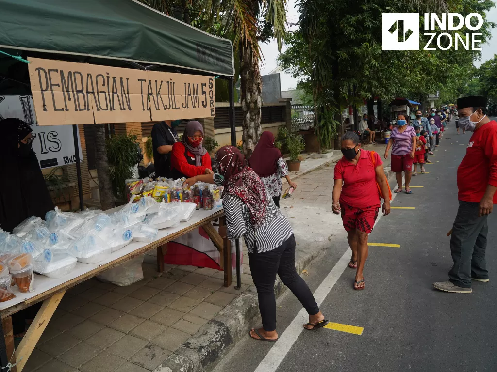 Warga menerapkan jarak aman (physical distancing) saat antre untuk mendapatkan takjil gratis di kawasan Cempaka Putih Raya, Jakarta, Selasa (12/5/2020). (INDOZONE/Arya Manggala)