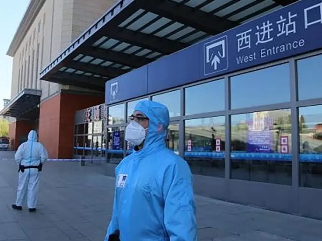 Petugas di Tiongkok memakai baju hazmat saat berjaga di depan sebuah fasilitas transportasi umum.(Weibo.scmp)