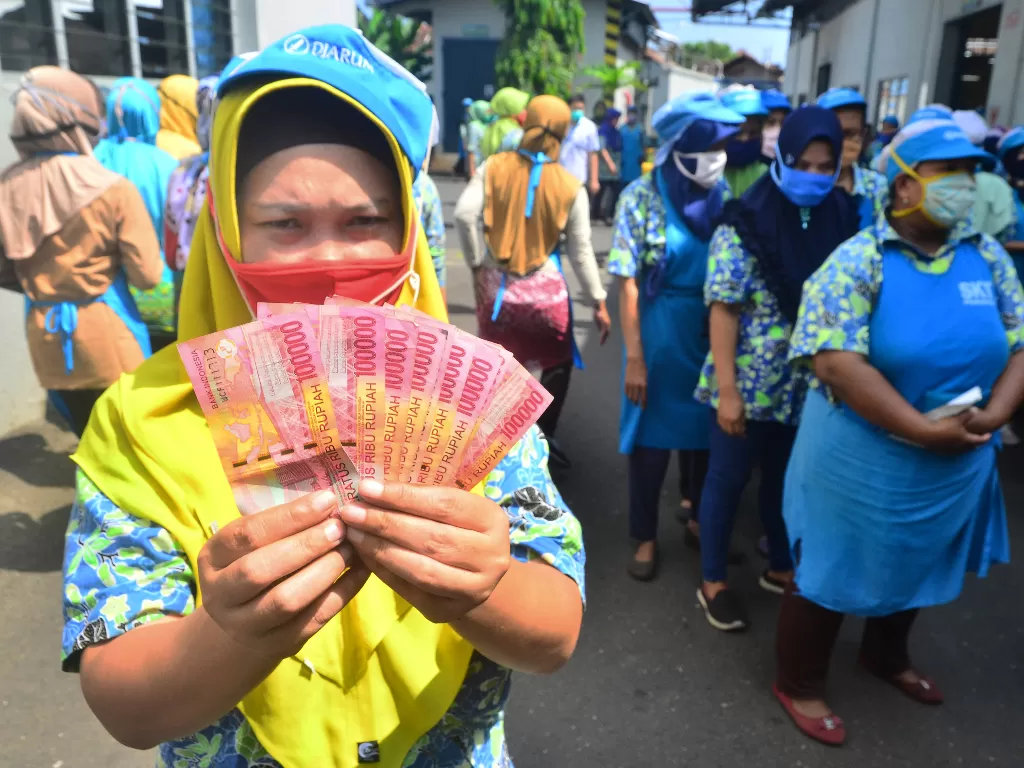 Ilustrasi pekerja menunjukkan uang Tunjangan Hari Raya (THR) Lebaran yang diterimanya di pabrik rokok PT Djarum, Kudus, Jawa Tengah, Selasa (12/5/2020). (ANTARA FOTO/Yusuf Nugroho)