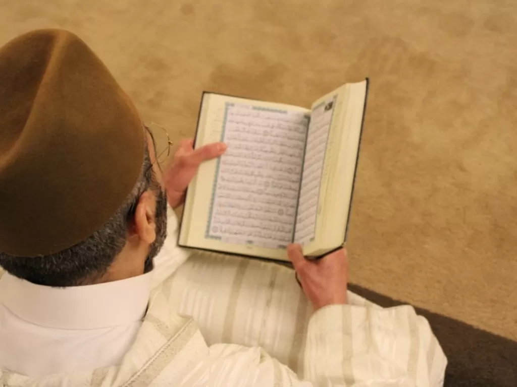 Ilustrasi pria sedang membaca Al Quran. (Unsplash/ Rachid Oucharia)