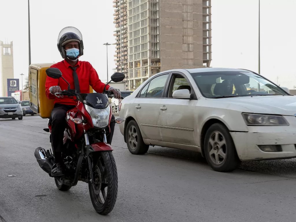 Ilustrasi: seorang pengendara memakai masker saat melewati jalan di Riyadh. (REUTERS/Ahmed Yosri)