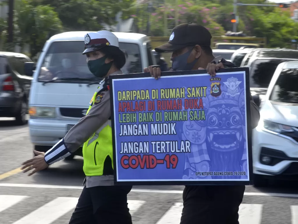 Petugas kepolisian melakukan sosialisasi pencegahan COVID-19 kepada pengendara yang melintas di Denpasar, Bali (ANTARA FOTO/Fikri Yusuf)