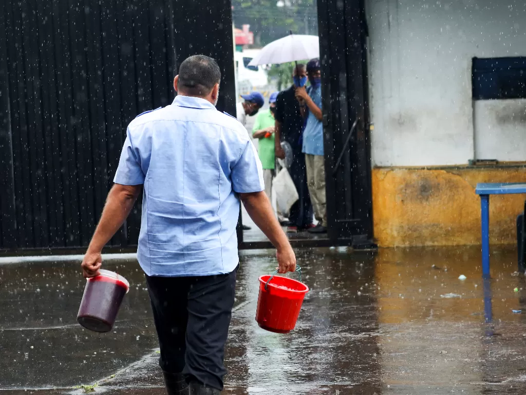 Warga Venezuela saat keluar membawa darah sapi dari rumah jagal. (REUTERS/Carlos Eduardo Ramirez)
