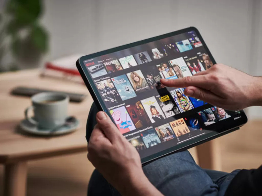 Ilustrasi orang sedang menikmati layanan Netflix di tablet. (Istimewa)