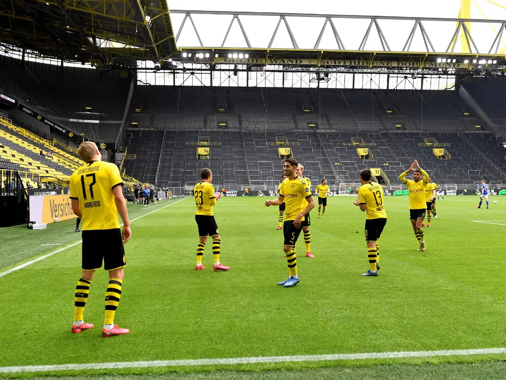 Pemain Borussia Dortmund Erling Braut Haaland merayakan gol bersama rekannya dengan protokol jaga jarak saat melawan Schalke 04 di stadion Signal Iduna Park, Dortmund, Sabtu (16/5/2020). (Martin Meissner/Pool via REUTERS)
