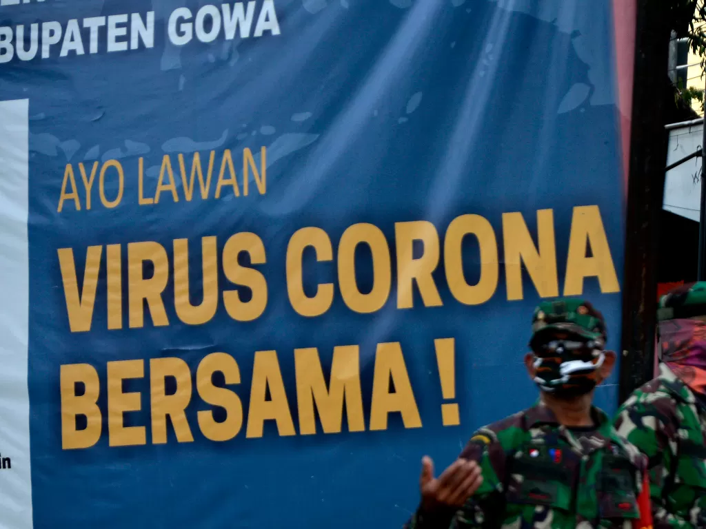 Anggota TNI melakukan penjagaan di dekat spanduk bertuliskan Ayo Lawan Virus Corona Bersama di Kabupaten Gowa, Sulawesi Selatan. (ANTARA FOTO/Abriawan Abhe)