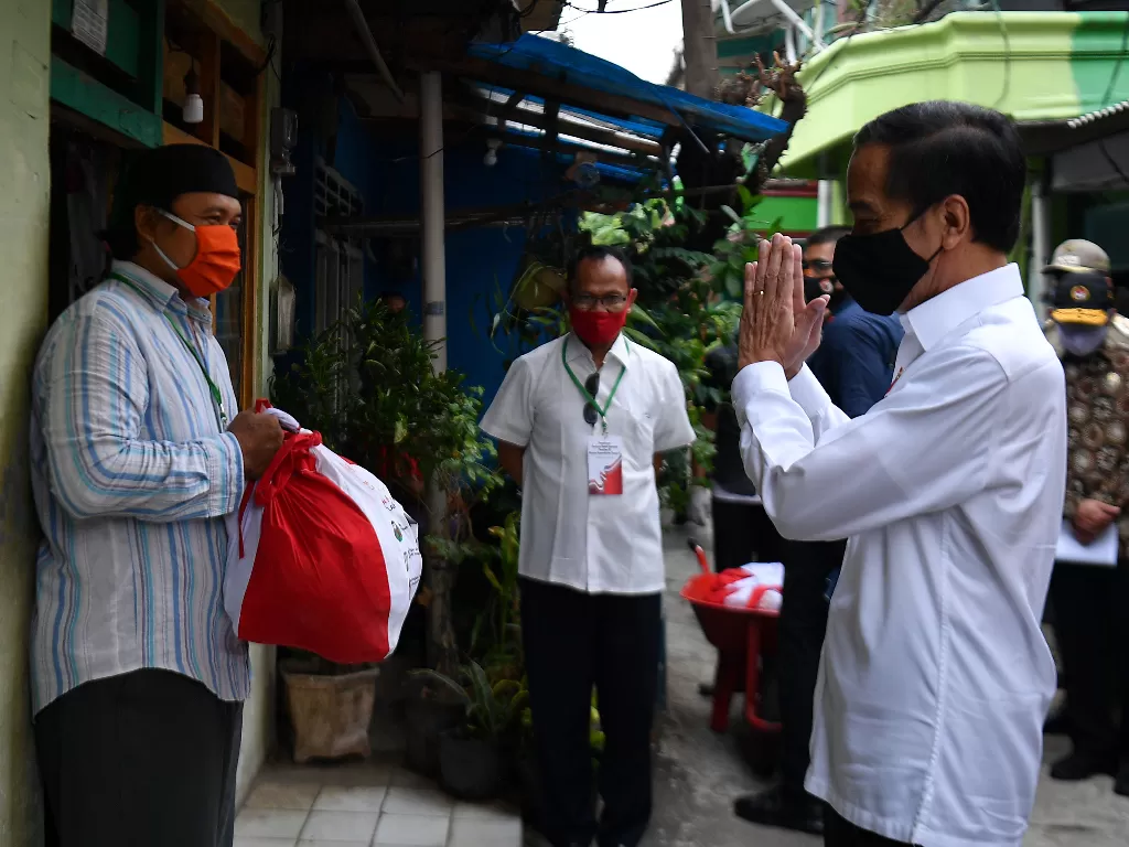 Presiden Joko Widodo (kanan) memberi salam kepada warga saat meninjau proses distribusi sembako tahap ketiga bagi masyarakat kurang mampu dan terdampak COVID-19 di kawasan Johar Baru, Jakarta Pusat, Senin (18/5/2020). (ANTARA FOTO/Sigid Kurniawan)