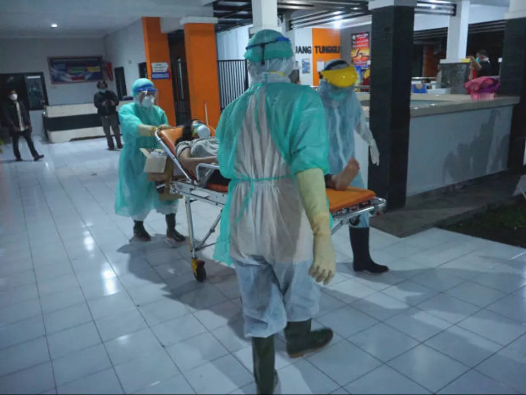 Perawat mengenakan pakaian APD saat membawa pasien dalam pengawasan COVID-19. (FOTO: ANTARA/Destyan Sujarwoko)