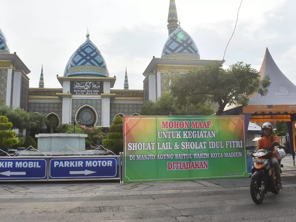 Pengendara motor melintas di dekat papan pengumuman di halaman Masjid Agung Baitul Hakim Kota Madiun, Jawa Timur, Jumat (15/5/2020). (ANTARA FOTO/Siswowidodo)