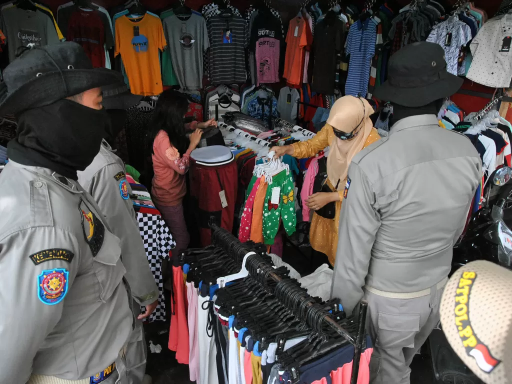 Anggota Satpol PP Kota Bogor mengawasi pedagang kaki lima (PKL) yang merapikan barang dagangannya saat penertiban di kawasan Pasar Anyar, Kota Bogor, Jawa Barat. (ANTARA/Arif Firmasnyah)