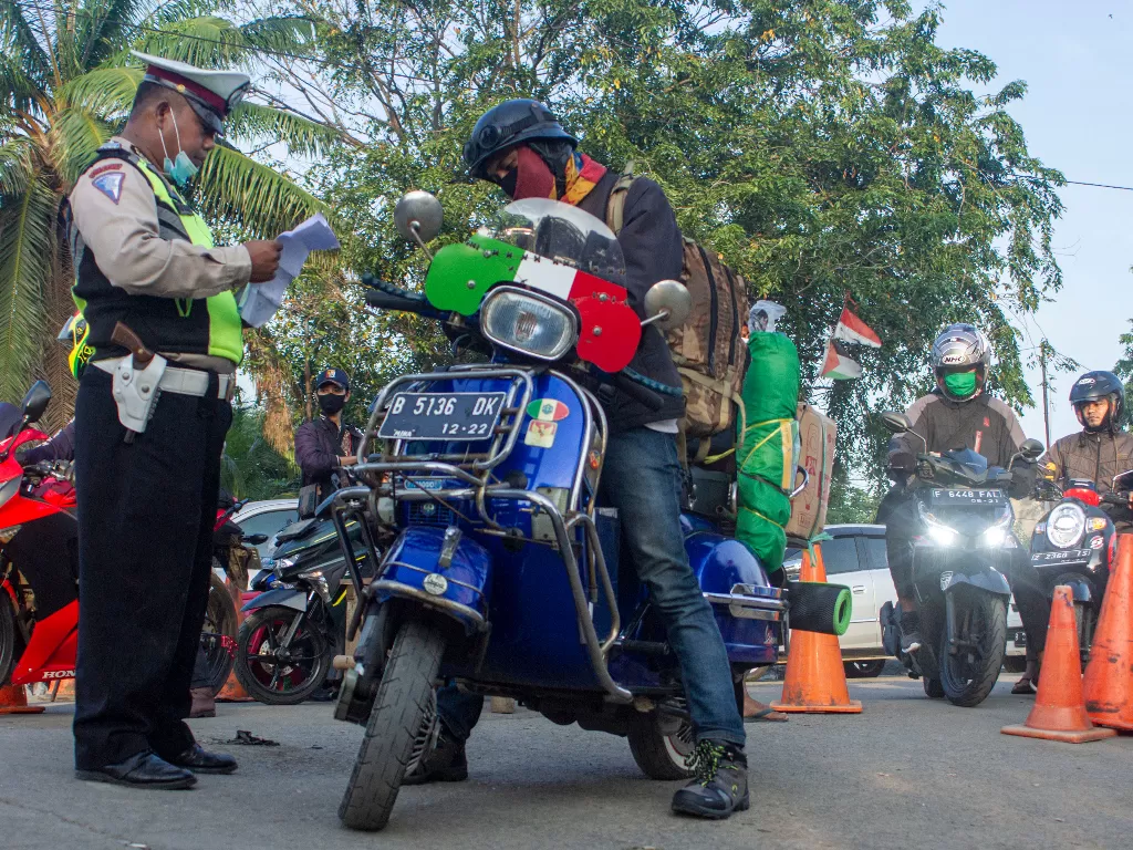 Petugas gabungan memeriksa surat keterangan pengendara roda dua saat pemeriksaan kendaraan pemudik di Perbatasan Karawang-Bekasi, Jawa Barat, Jumat (22/5/2020). (ANTARA FOTO/M Ibnu Chazar)