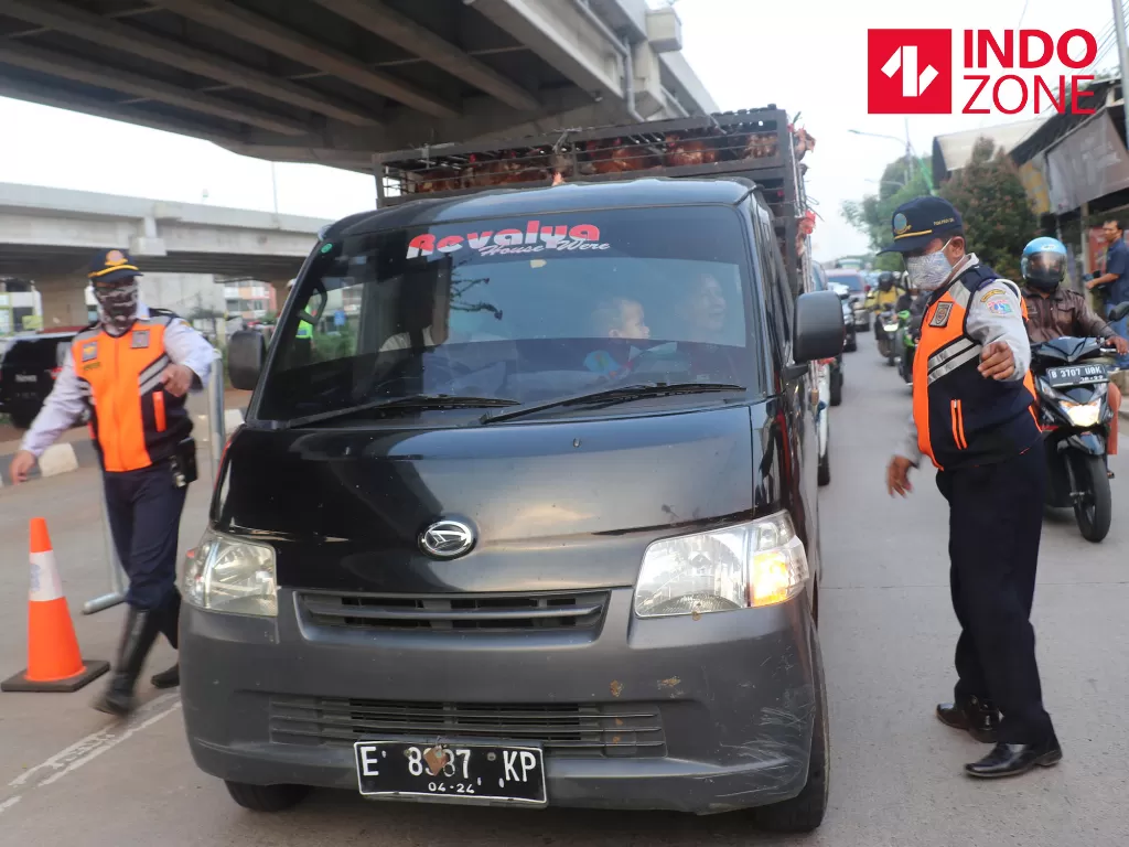 Petugas kepolisian memeriksa kendaraan yang melintas di cek poin Lampiri, Kalimalang, Jakarta, Jumat (22/5/2020). (INDOZONE/Febio Hernanto)