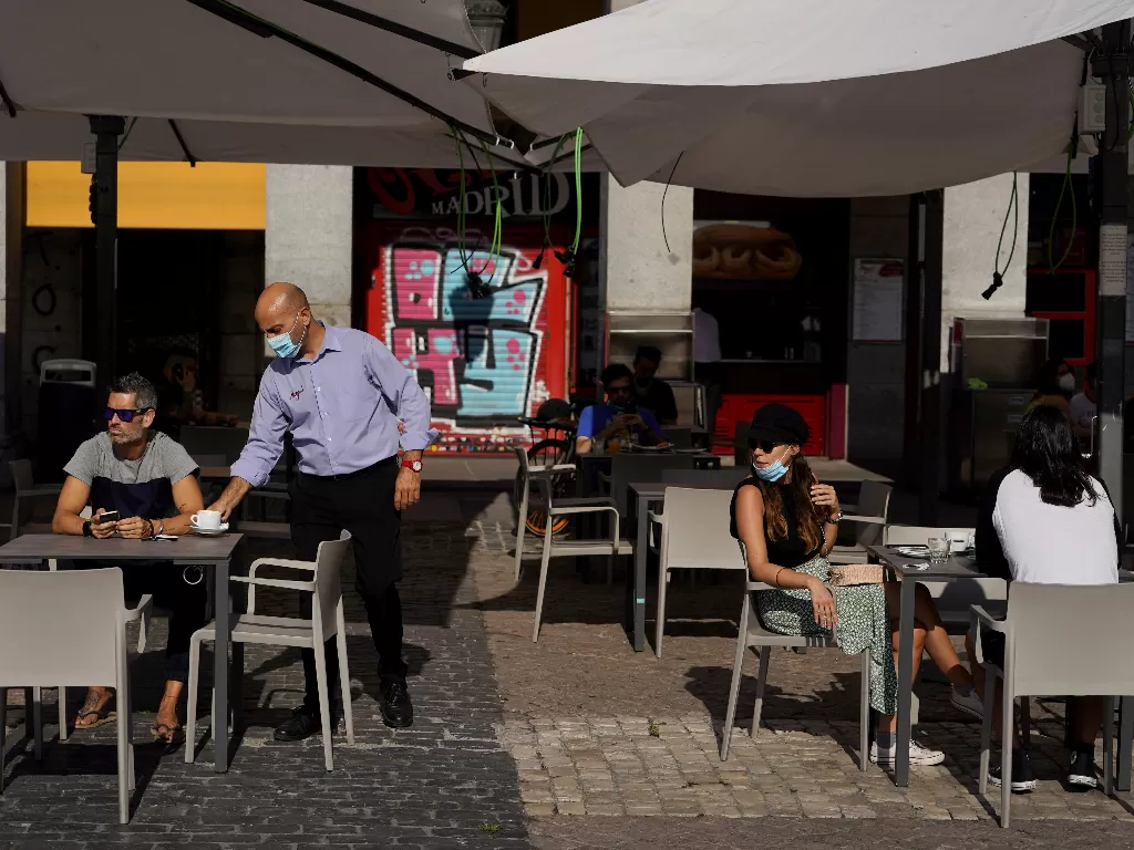 Sejumlah warga yang sedang menikmati makanan di sebuah kafe di Spanyol. (photo/REUTERS/Juan Medina)