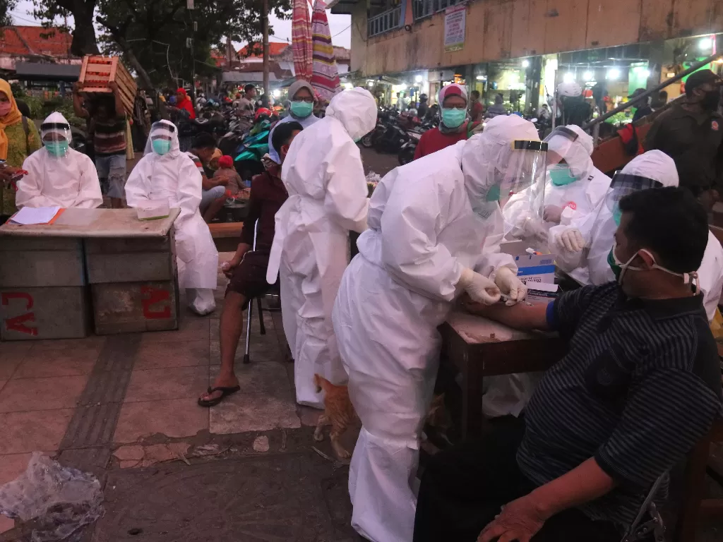 Petugas melakukan pemeriksaan cepat COVID-19 (Rapid Test) terhadap warga di Pasar Keputran, Surabaya (ANTARA FOTO/Didik Suhartono)