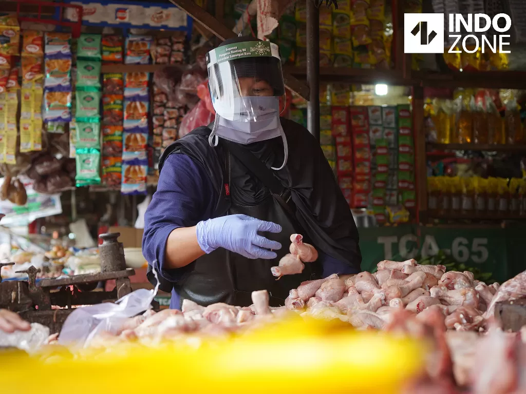 Pedagang daging ayam menggunakan plastik pelindung wajah atau face shield saat berjualan di Pasar Kemiri Muka, Depok, Jawa Barat, Jumat (1/5/2020). (INDOZONE/Arya Manggala)