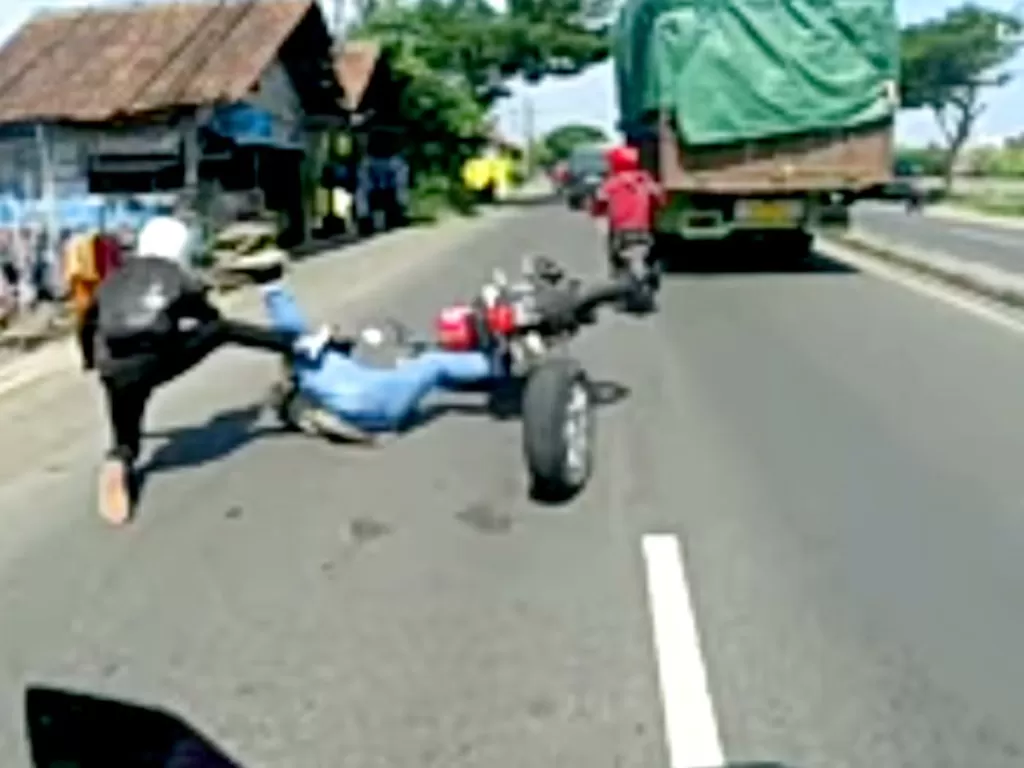 Screenshot pengendara motor yang terjatud usai ban cadangan mobil di depannya terlepas. (Facebook/Sedikit Viral)