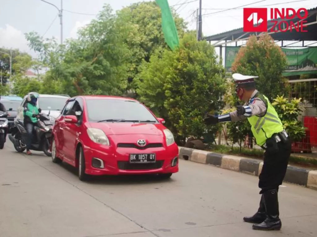 Petugas memberhentikan kendaraan guna memeriksa kelengkapan Surat Izin Keluar Masuk (SIKM) Jakarta di Cek Poin PSBB Lampiri, Kalimalang, Jakarta. (INDOZONE/Febio Hernanto)