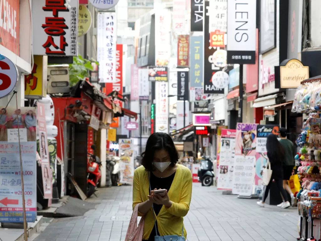 Warga di distrik Seoul memakai masker saat beraktivitas di luar rumah. (REUTERS/Kim Hong-Ji)