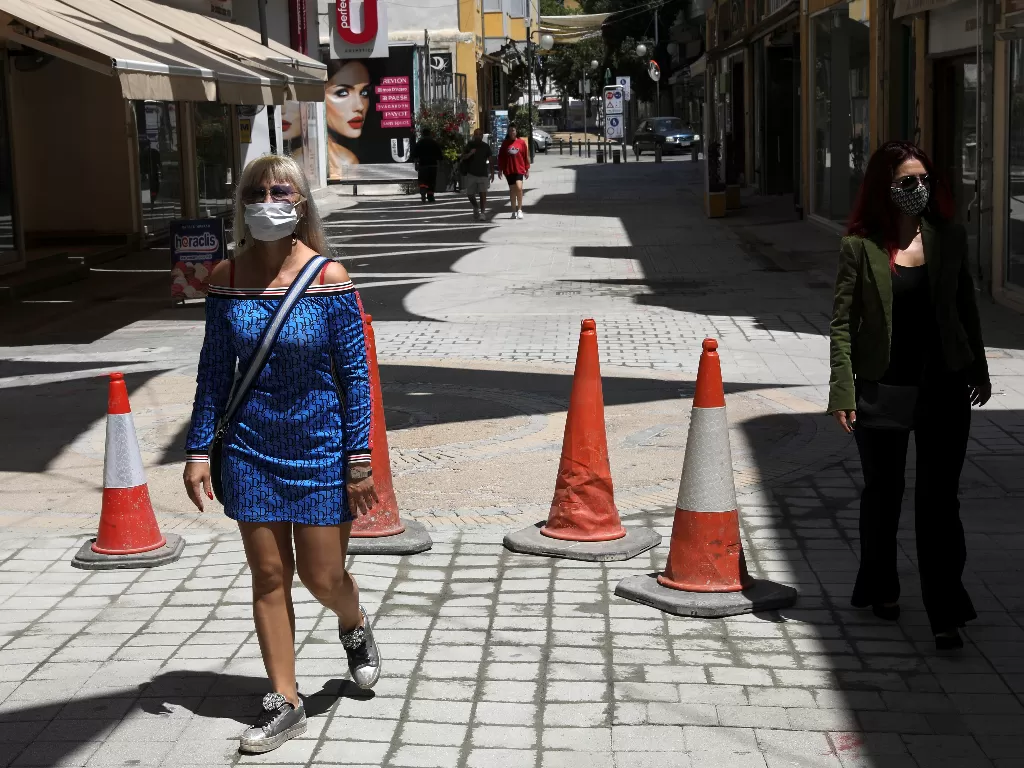 Warga mengenakan masker saat berjalan di sebuah pusat pertokoan di kota Nicosia, Siprus. (REUTERS/Yiannis Kourtoglou)