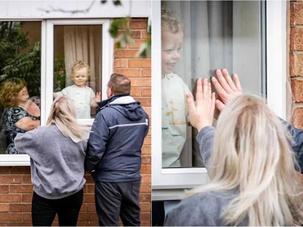 Potret perawat yang lepas rindu kepada anak lewat jendela kaca. (Pete Ashton/SWNS)