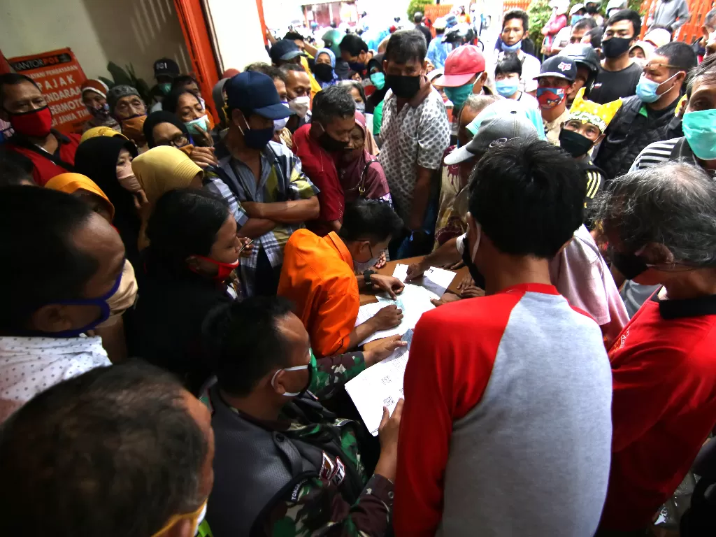 Warga berdesakan saat mengantre pembagian Bantauan Sosial Tunai (BLT) di Kantor Pos Banyuwangi, Jawa Timur. (ANTARA/Budi Candra Setya)