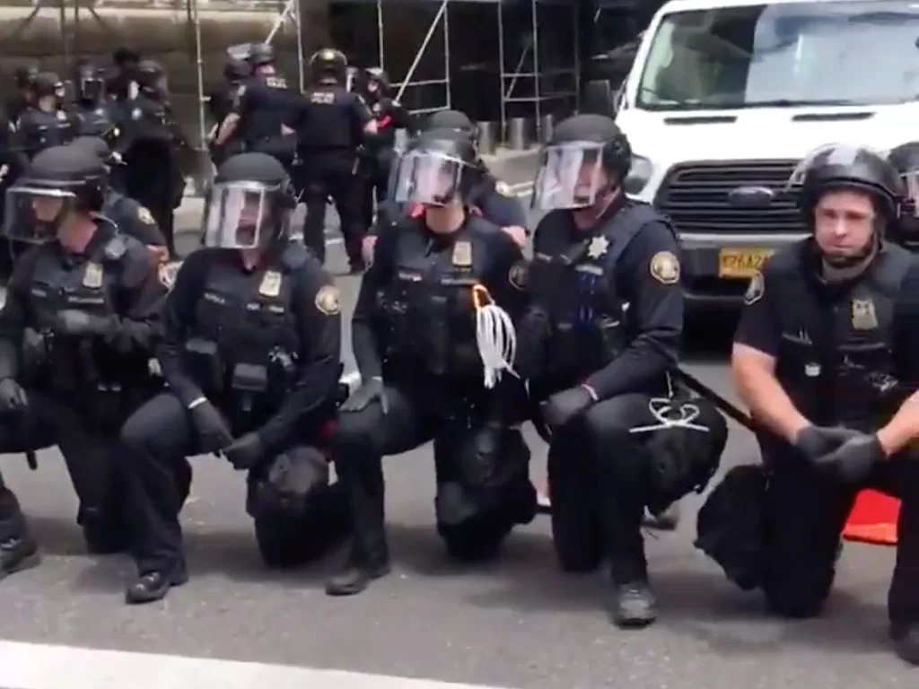 Sejumlah polisi berlutut dalam solidaritas dengan pengunjuk rasa di Portland, Oregon, AS, 31 Mei 2020. (PAIGE BARETTA via REUTERS)