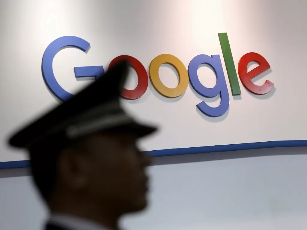 Seorang polisi sedang berdiri di depan logo Google (photo/REUTERS/Aly Song)