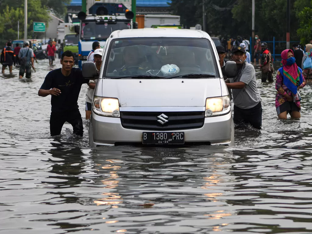 Warga mendorong mobil yang mogok saat melintasi banjir air rob di kawasan Muara Baru, Penjaringan, Jakarta Utara, Jumat (5/6/2020). (ANTARA FOTO/M Risyal Hidayat)