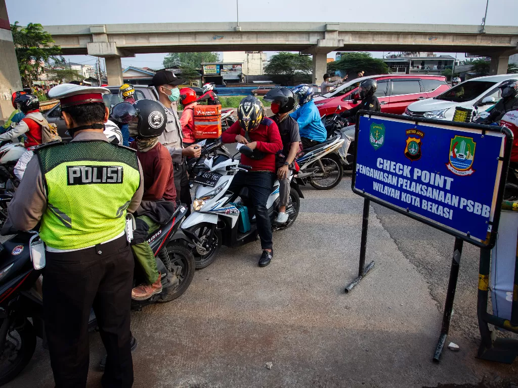 Petugas melakukan pengawasan terhadap kendaraan yang melintasi Check Point Pembatasan Sosial Berskala Besar (PSBB) di kawasan Kalimalang, Bekasi. (ANTARA FOTO/Dhemas Reviyanto)