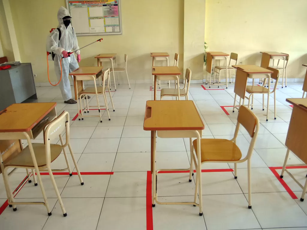 Petugas sekolah menyemprot cairan disinfektan pada kelas yang telah diatur jarak antar siswa di SMK Kosgoro, Kota Bogor, Jawa Barat, Kamis (4/6/2020). (ANTARA/Arif Firmasnyah)
