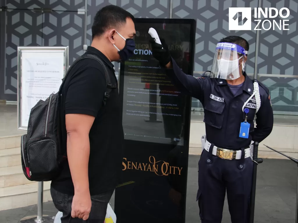 Petugas mengecek suhu tubuh pengunjung di Senayan City, Jakarta, Selasa (9/6/2020). (INDOZONE/Febio Hernanto)