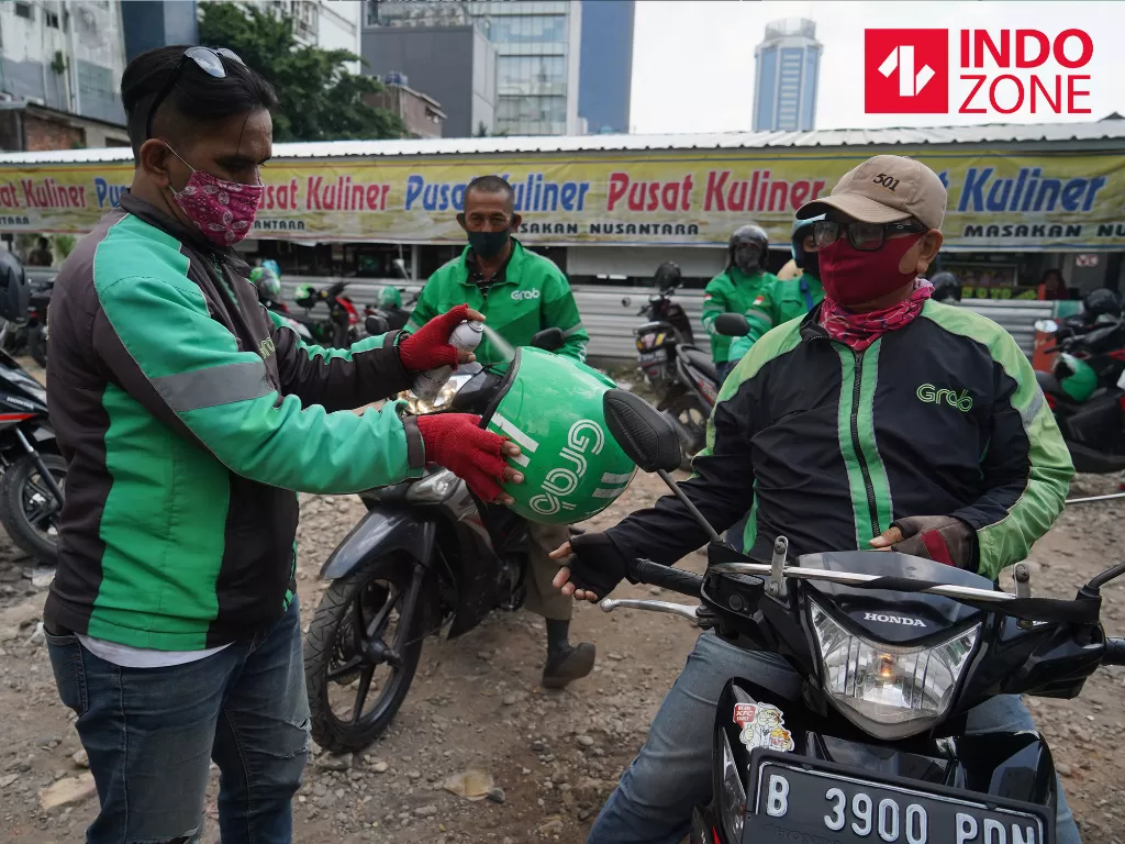 Pengemudi ojol melakukan penyemprotan disinfektan motor dan helm di kawasan Stasiun Sudirman, Jakarta, Senin (8/6/2020). (INDOZONE/Arya Manggala)