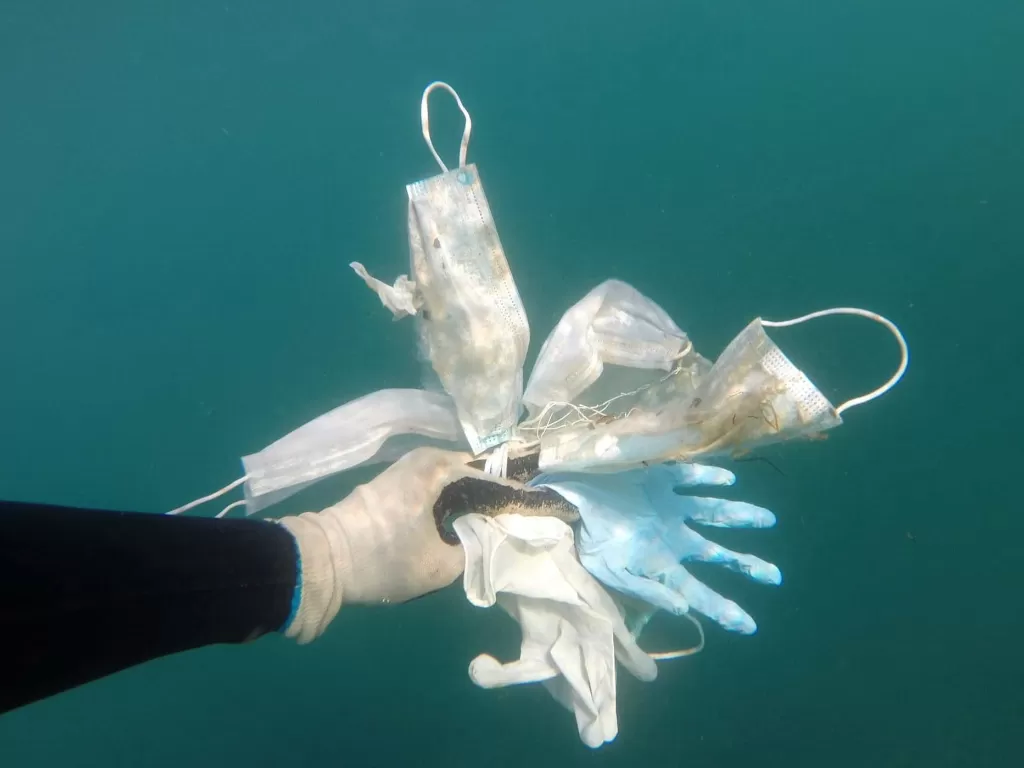 Seorang penyelam membawa masker dan sarung tangan yang dipungut dari dasar laut Mediterania di tengah pandemi Covid-19.  (Laurent Lombard/Operation Mer Propre via REUTERS)