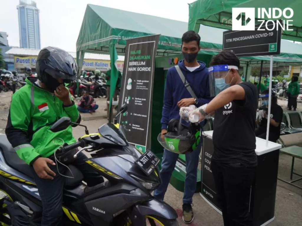 Petugas melakukan penyemprotan disinfektan terhadap helm yang akan digunakan penumpang di kawasan Stasiun Sudirman, Jakarta, Senin (8/6/2020). (INDOZONE/Arya Manggala)