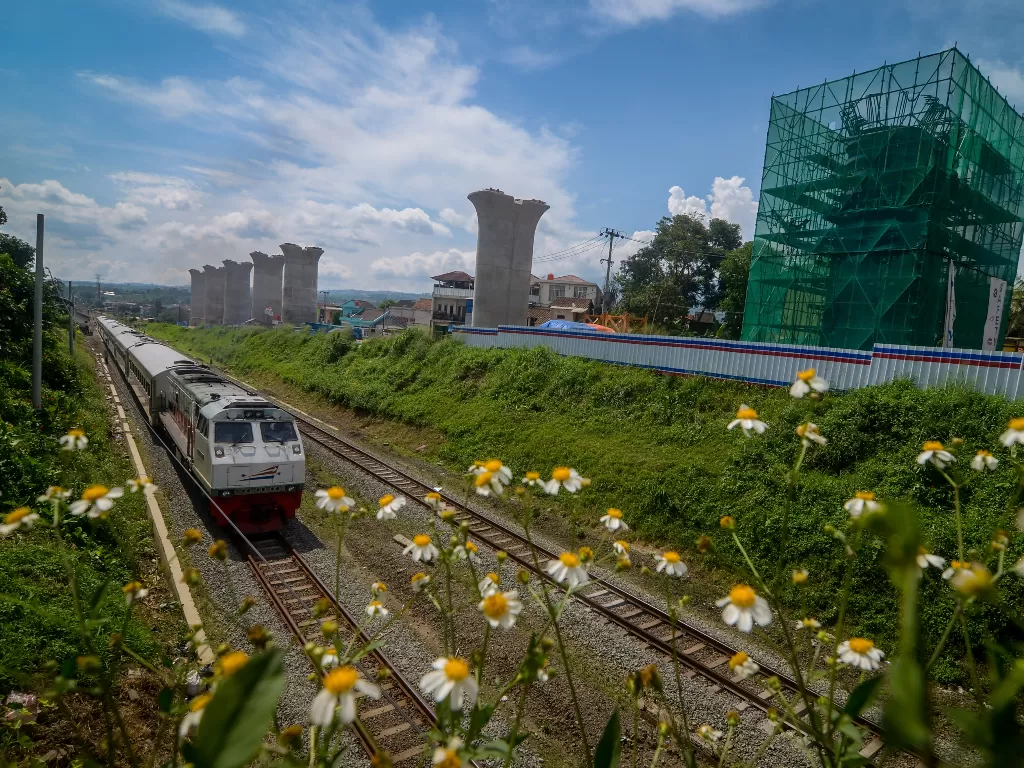 Kereta api melintas di samping proyek pembangunan jalur kereta cepat Jakarta-Bandung di Cipatat, Kabupaten Bandung Barat, Jawa Barat, Rabu (27/5). (ANTARA FOTO/Raisan Al Farisi)