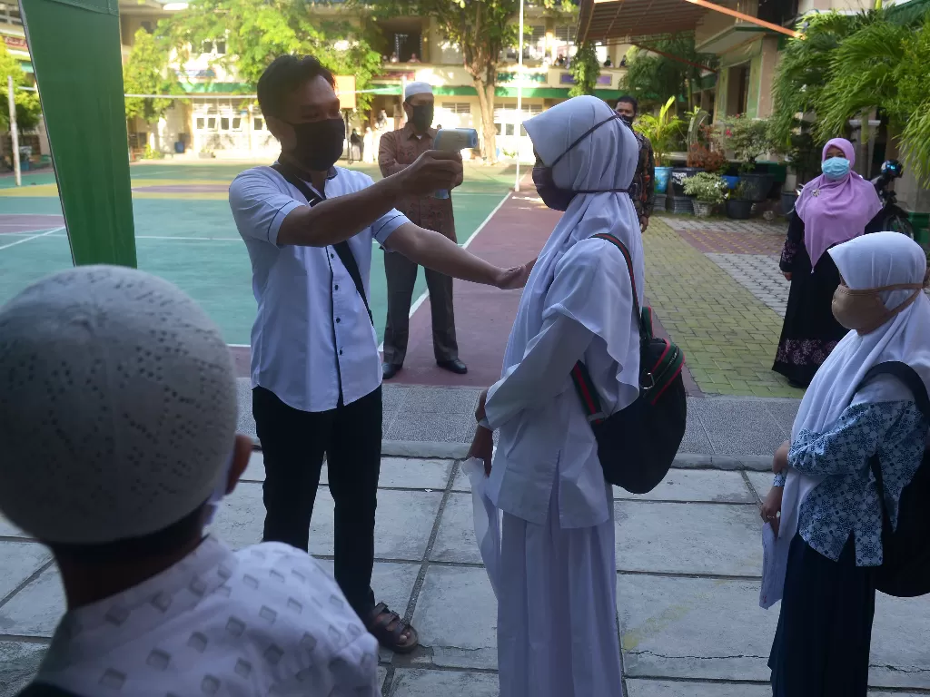 Seorang guru memeriksa suhu badan calon murid yang akan mengikuti ujian berbasis komputer dan tes kemampuan membaca Al Quran di Madrasah Tsanawiyah Negeri (MTsN) di Banda Aceh, Aceh. (ANTARA FOTO/Ampelsa)