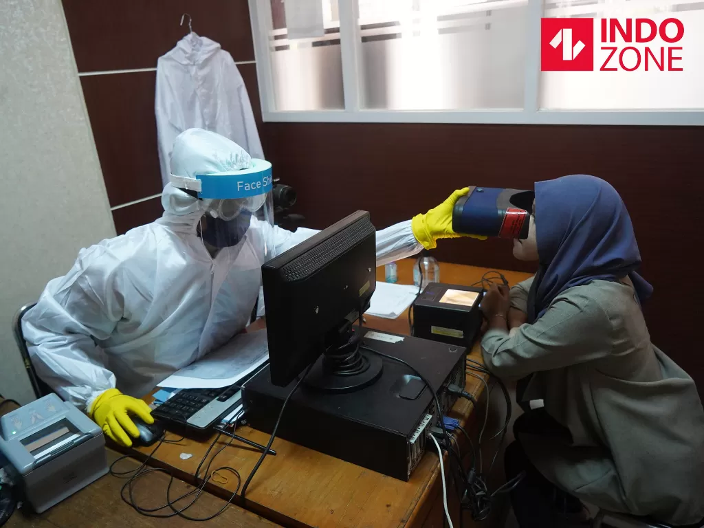 Petugas menggunakan pakaian Alat Pelindung Diri (APD) lengkap saat melakukan perekaman data pembuatan KTP Elektronik di Kantor Kecamatan Pondok Aren, Tangerang Selatan, Banten, Selasa (16/6/2020). (INDOZONE/Arya Manggala)