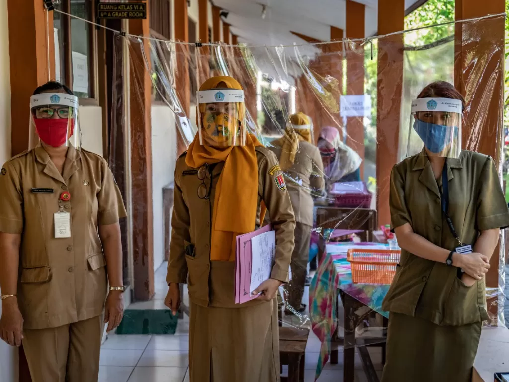 Sejumlah panitia Penerimaan Peserta Didik Baru (PPDB) mengenakan masker dan pelindung wajah di SDN Karangayu 02, Kelurahan Karangayu, Kota Semarang, Jawa Tengah, Senin (15/6/2020). (ANTARA FOTO/Aji Styawan)