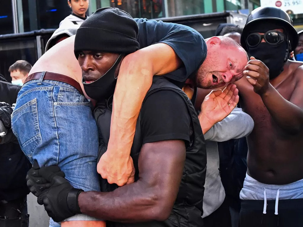 Patrick Hutchinson membawa pengunjuk rasa sayap kanan yang terluka ke tempat yang aman, saat demonstrasi Black Lives Matter di London, Inggris, 13 Juni 2020. (REUTERS/Dylan Martinez)