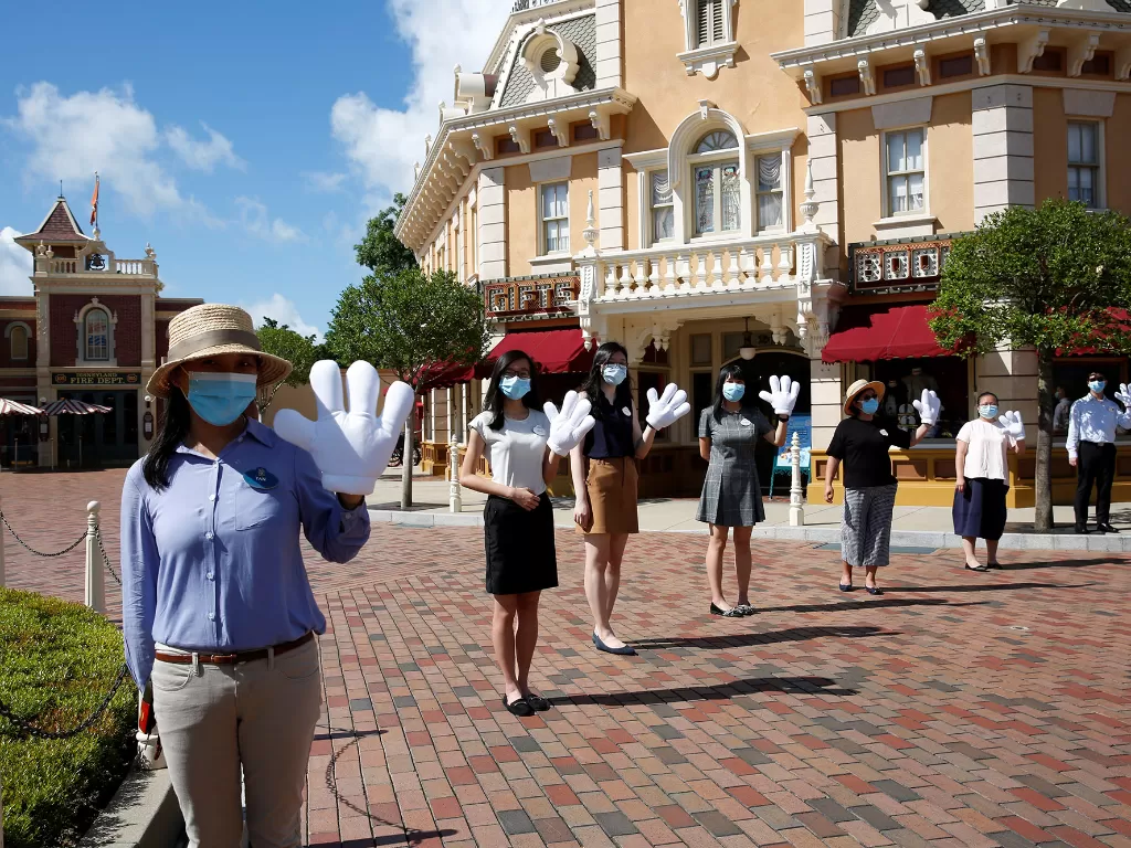 Karyawan taman hiburan Disneyland menyambut pengunjung saat pembukaan kembali tempat itu setelah sebelumnya ditutup akibat pandemi COVID-19, Hong Kong, Tiongkok, Kamis (18/6/2020). (REUTERS/Tyrone)