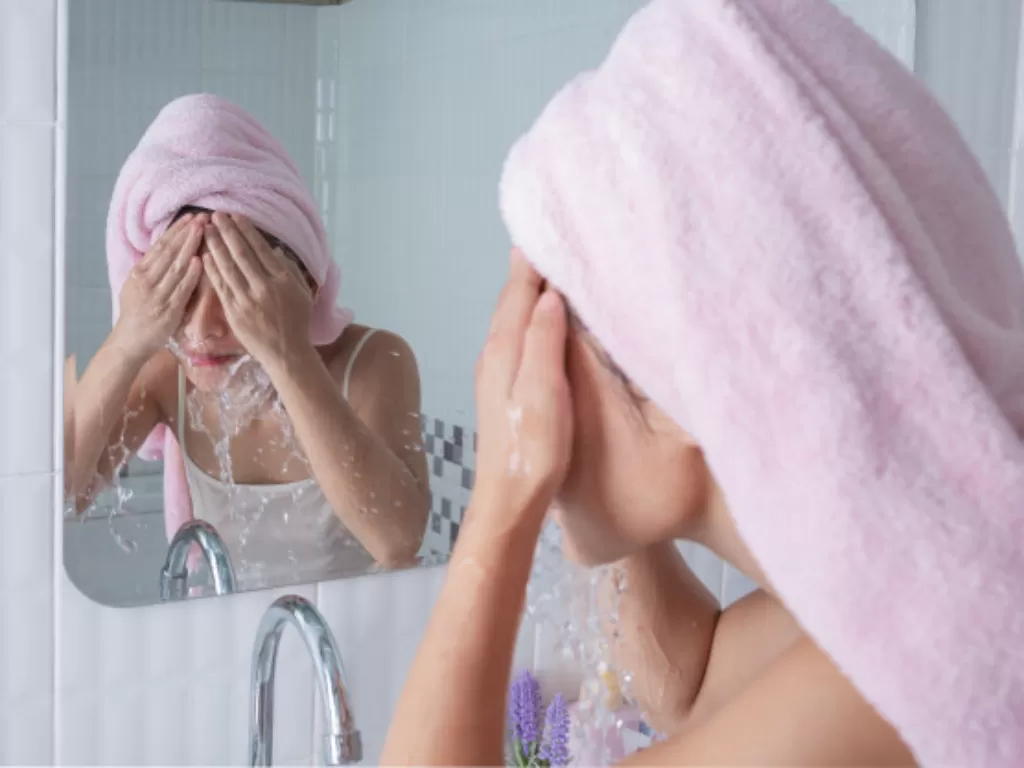 Ilustrasi wanita mencuci wajah dengan air dingin. (freepik/jcomp)