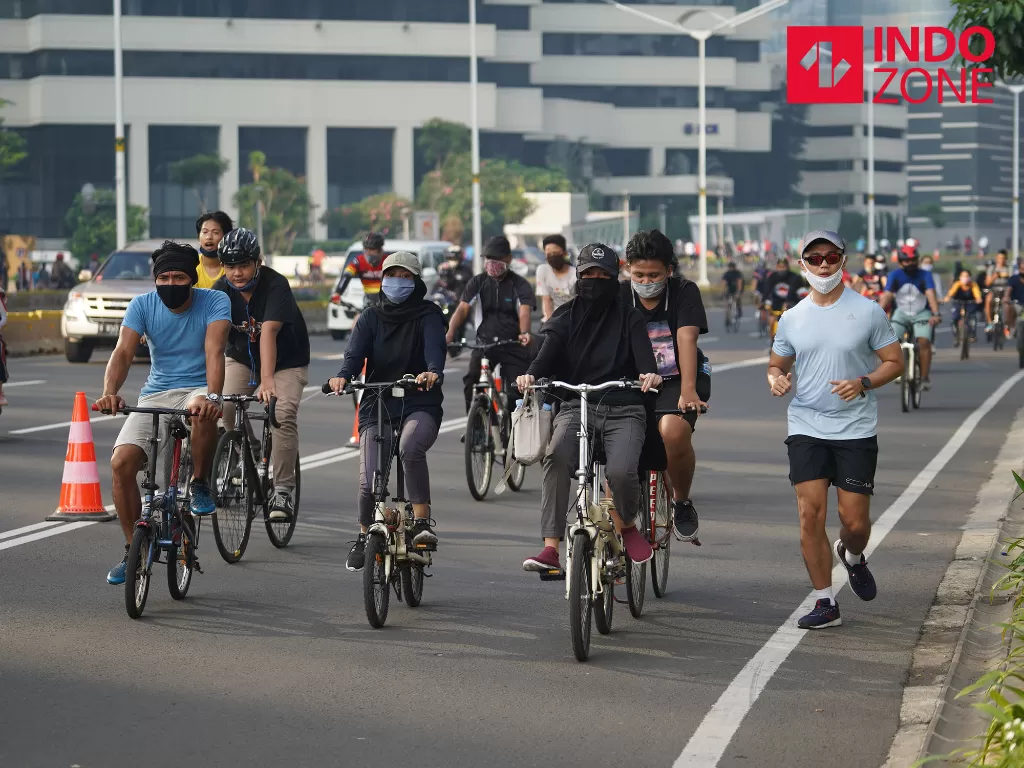 Warga mengenakan masker dan face shield saat bersepeda di kawasan Bundaran HI, Jakarta, Minggu (14/6/2020). (INDOZONE/Arya Manggala)
