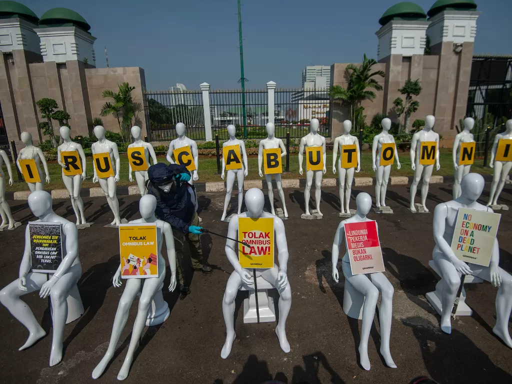 Aktivis Greenpeace menyemprotkan cairan disinfektan pada manekin saat aksi damai menolak pembahasan RUU Cipta Kerja di depan Kompleks Parlemen, Senayan, Jakarta, Senin (29/6/2020). (ANTARA FOTO/Aditya Pradana Putra)