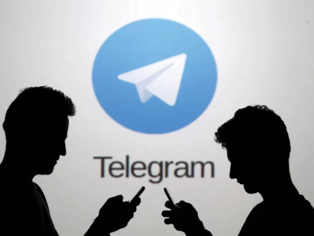 Ilustrasi 2 orang sedang berada di depan logo aplikasi Telegram (photo/REUTERS)